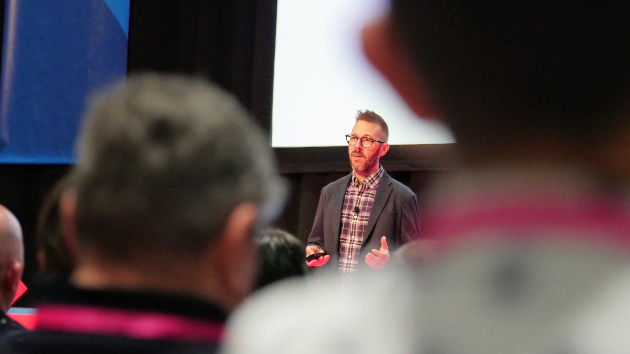Gregg Bernstein gives a talk at a conference, wearing a purple plaid shirt and a charcoal blazer